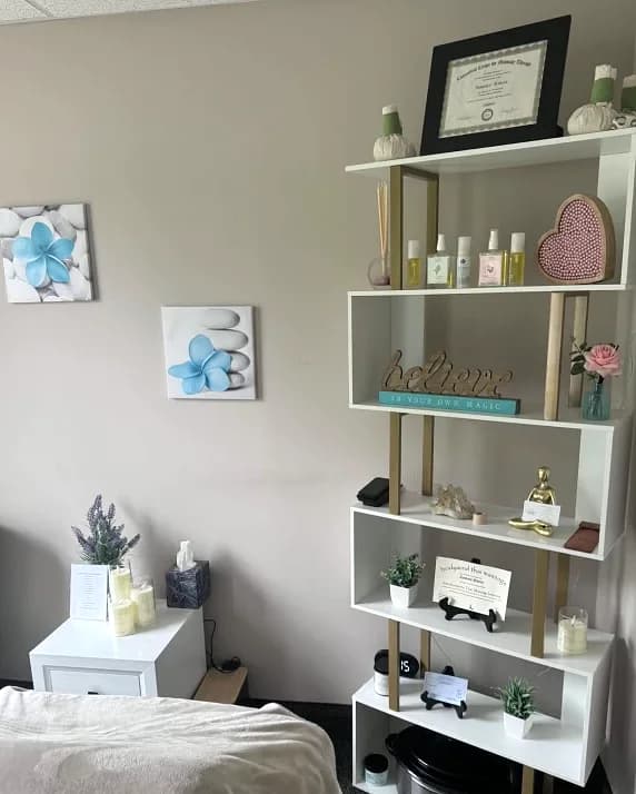 Shelf of massage oils, aromatherapy, and soft blue floral art